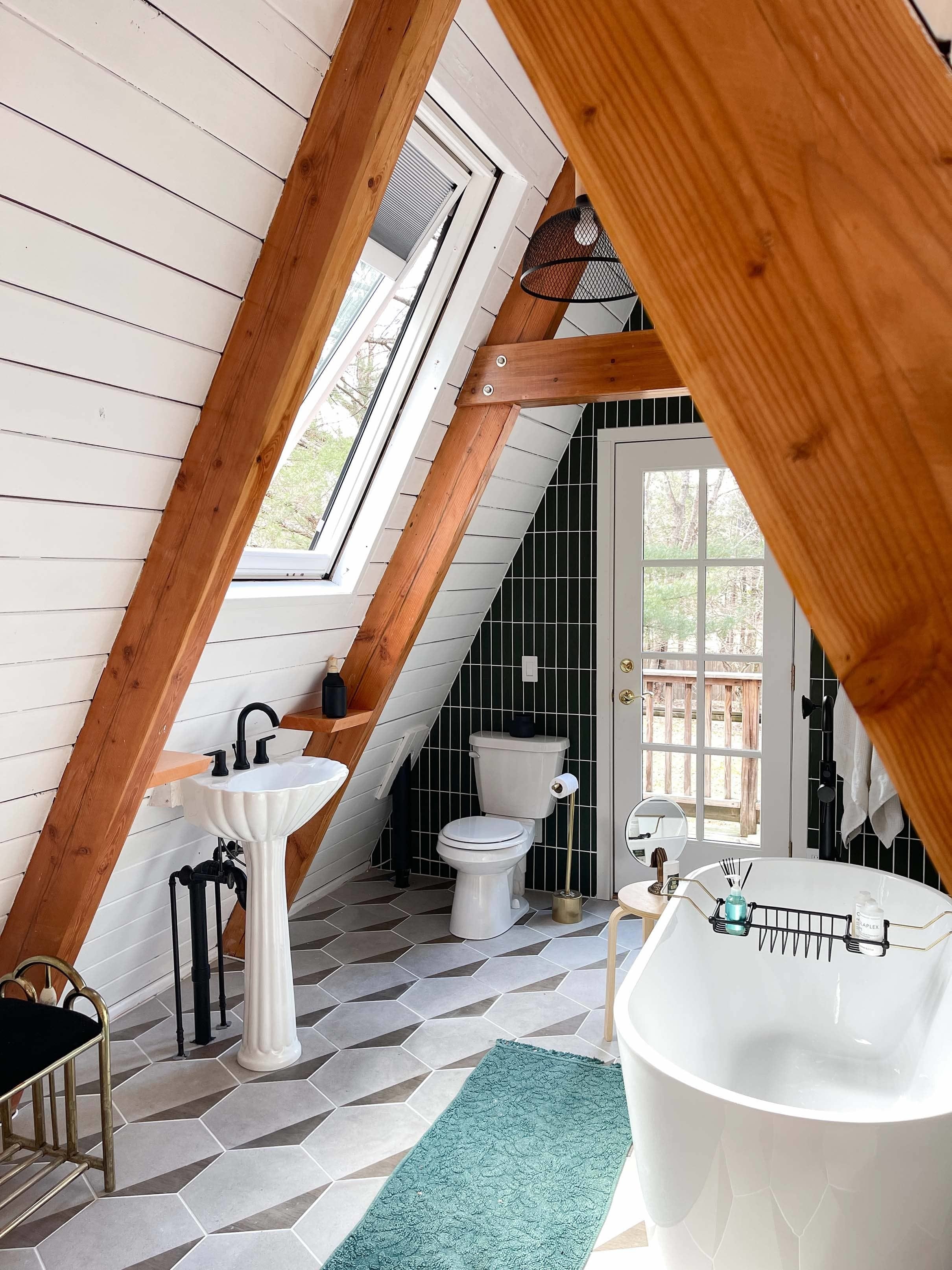 A-frame house bathroom with a skylight, free-standing bathtub and pedestal sink