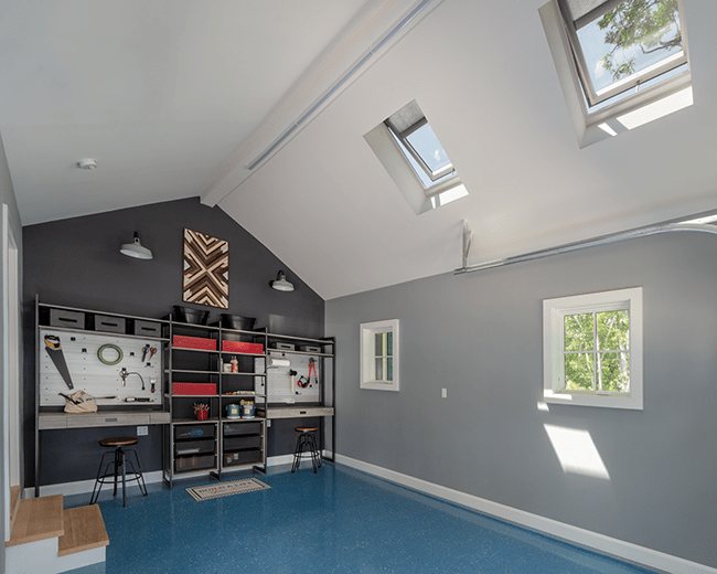 A garage with two skylights blue floor grey walls and workbench