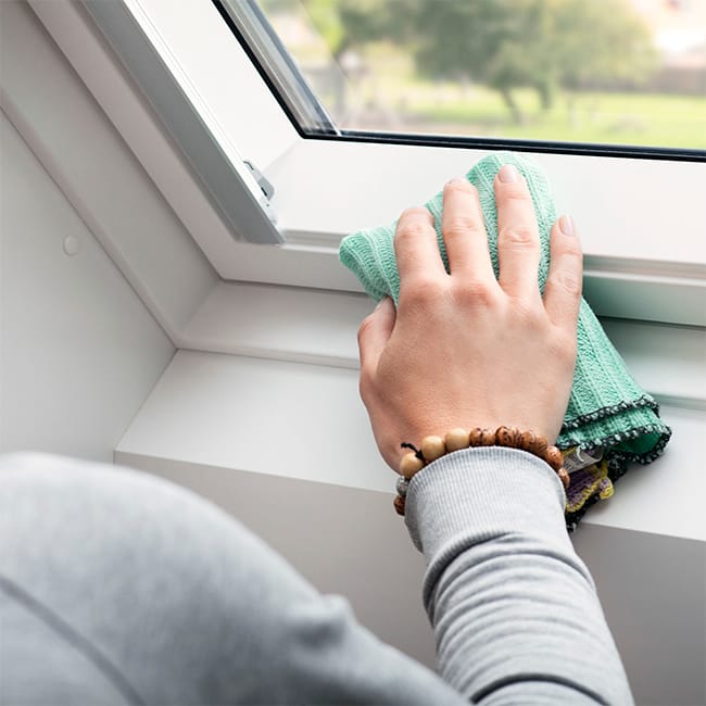 A hand wiping the interior skylight frame with a cloth