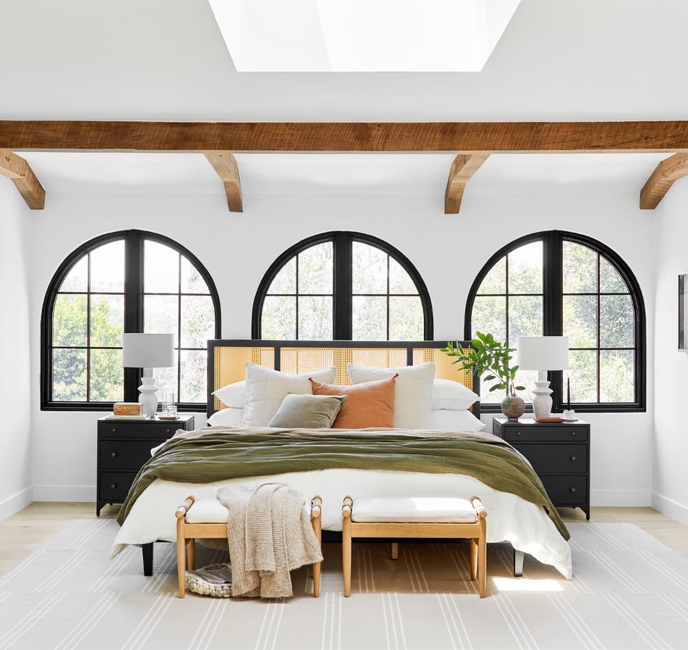 Interior designer Bobby Berk standing under a skylight in a bedroom