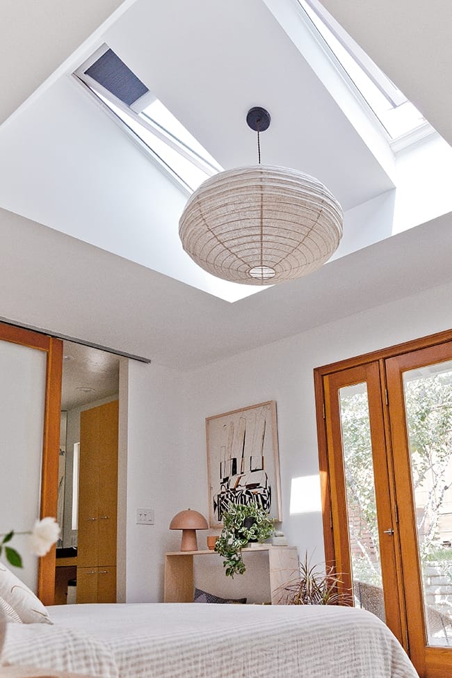 Bedroom with two skylights and paper lantern hanging in between over a bed