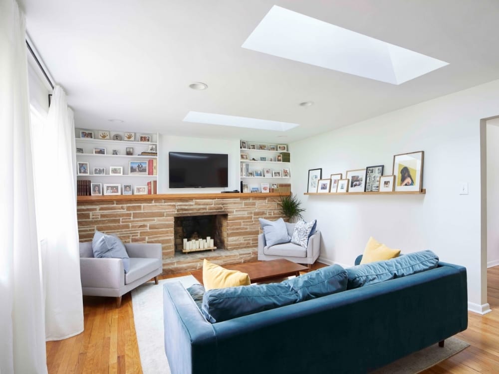 Living room blue sofa yellow pillows skylights stone fireplace