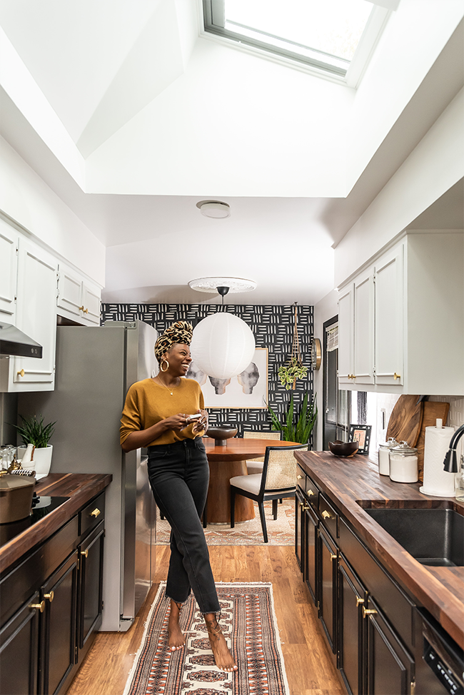 Carmeon Hamilton standing under a skylight in her black and white kitchen