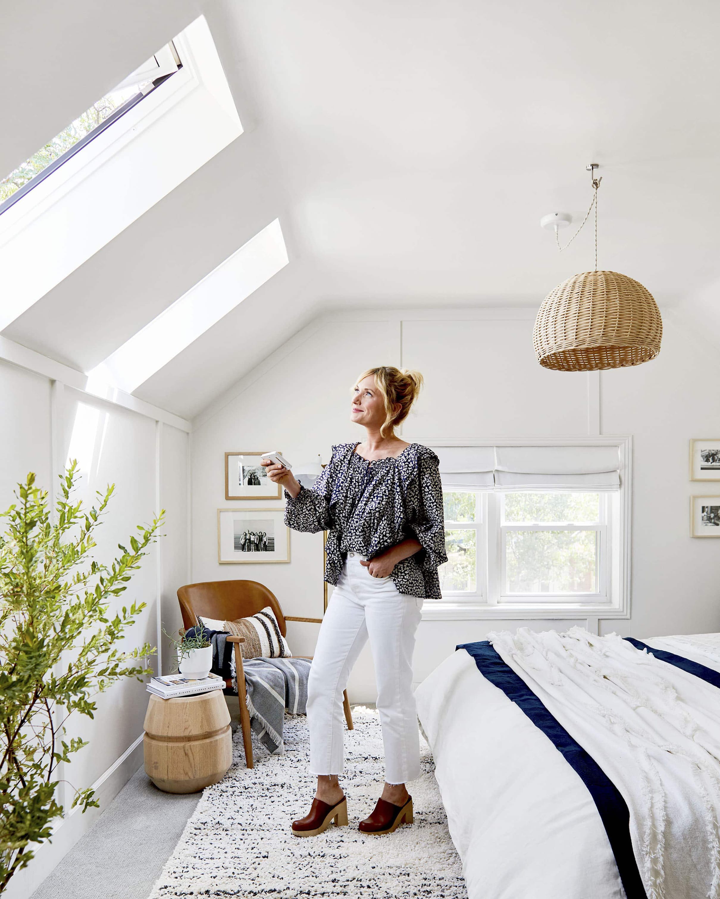 A woman stands in a bedroom under two skylights