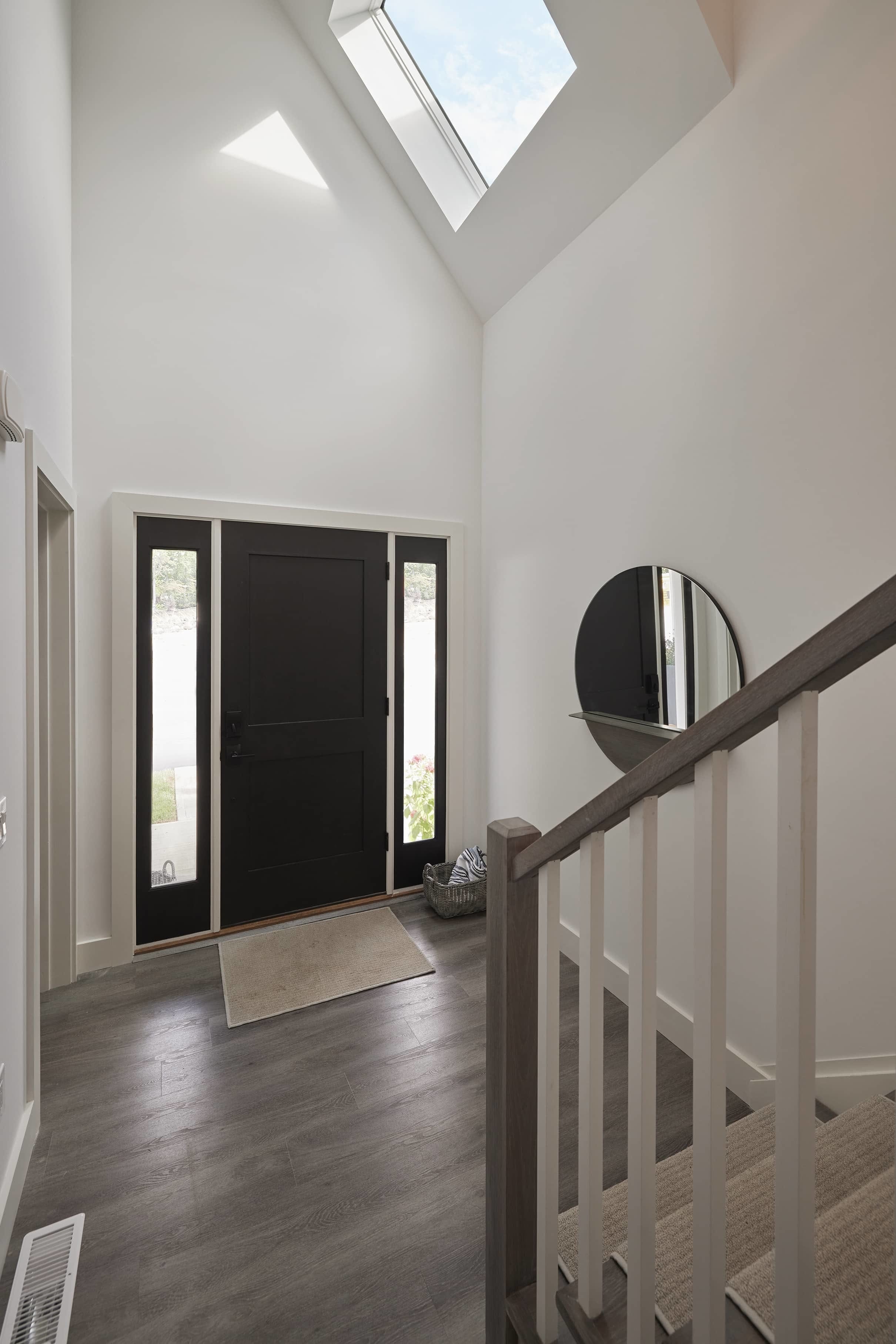 Front foyer skylight black door white walls stairs