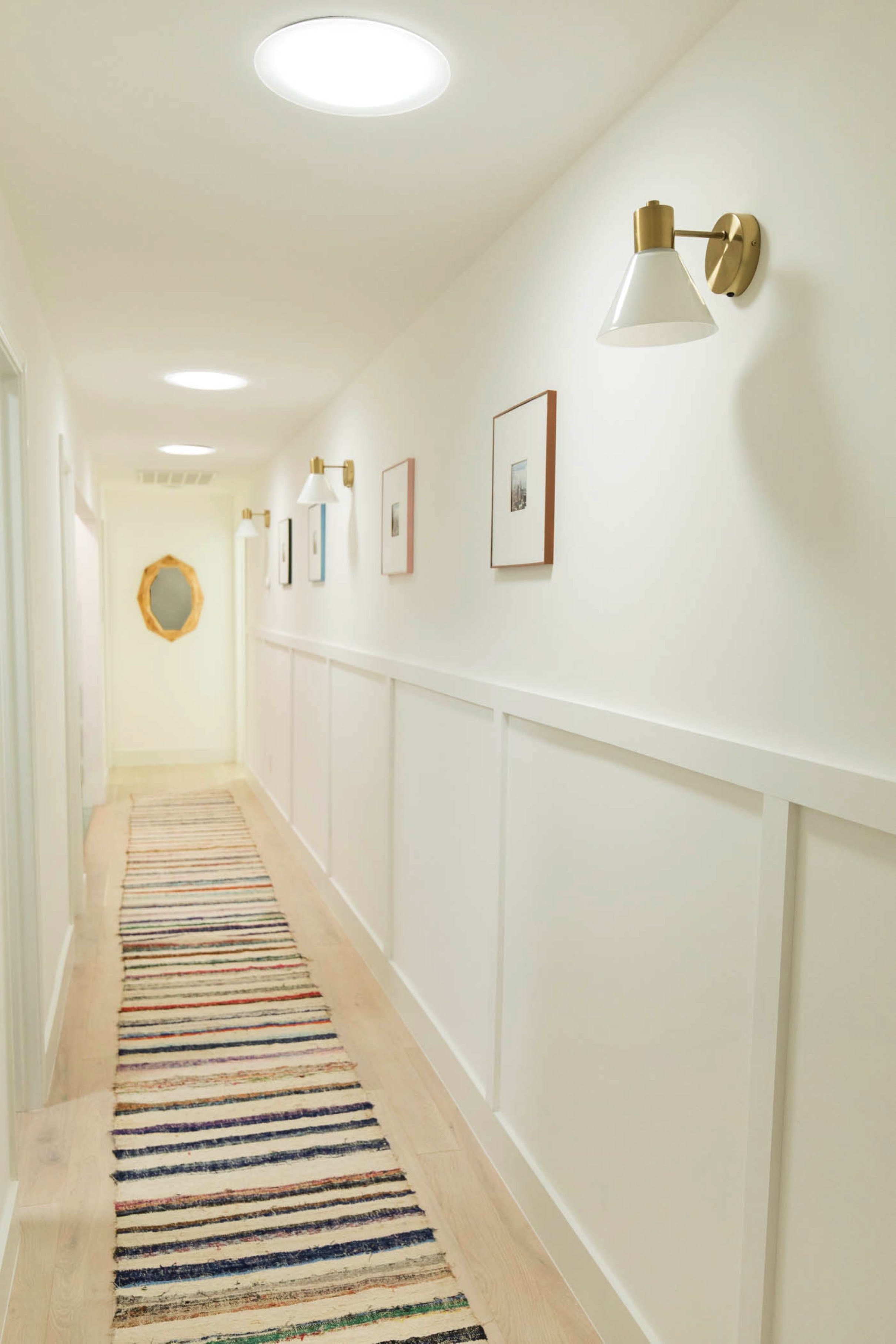 Hallway with three sun tunnel skylights, a striped runner rug and decorative wall panels