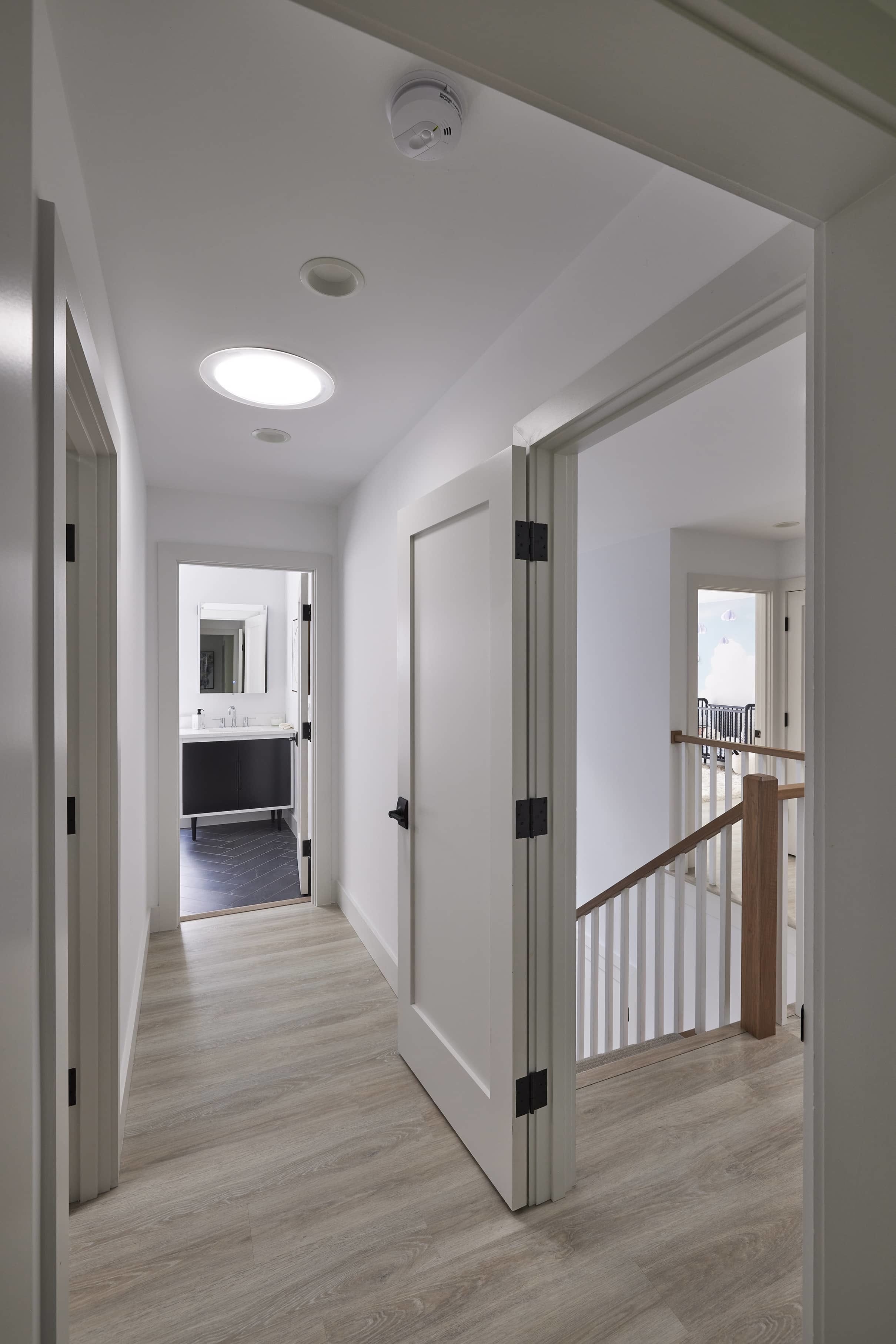 Hallway with wooden floor brightened by a VELUX Sun Tunnel skylight bathroom in the background