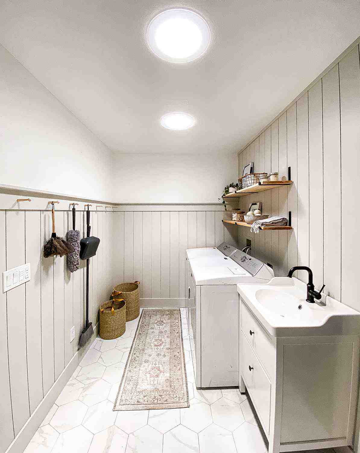 Two Sun Tunnel skylights brighten influencer Amanda Johnson's farm style laundry room with white wood paneling, light wood shelving and accents, and white sink and appliances.