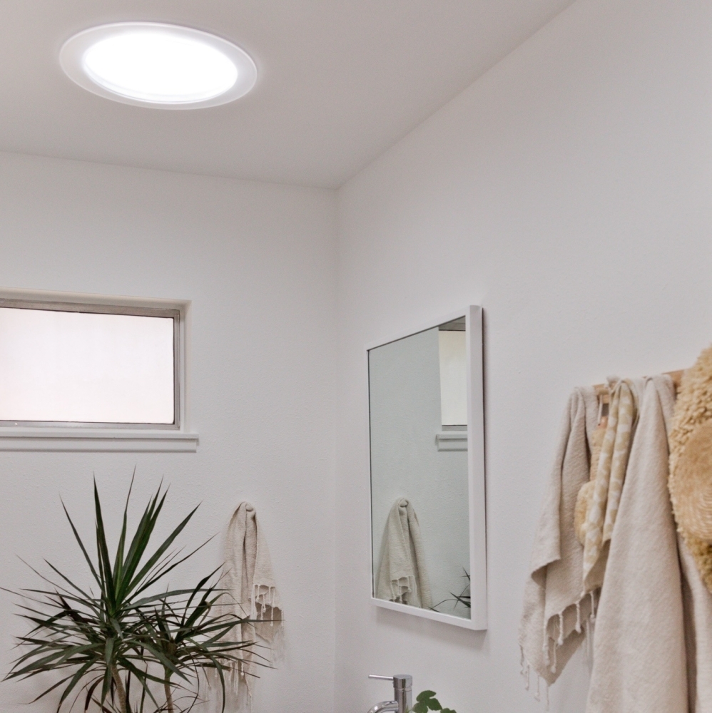 Side by side photos of the same bathroom showing it before and after a VELUX Sun Tunnel skylight has been installed.