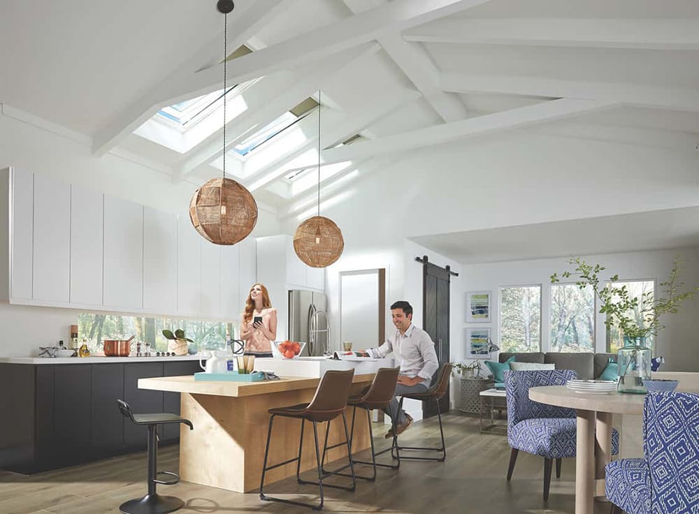 Two people around an island in a kitchen with two skylights