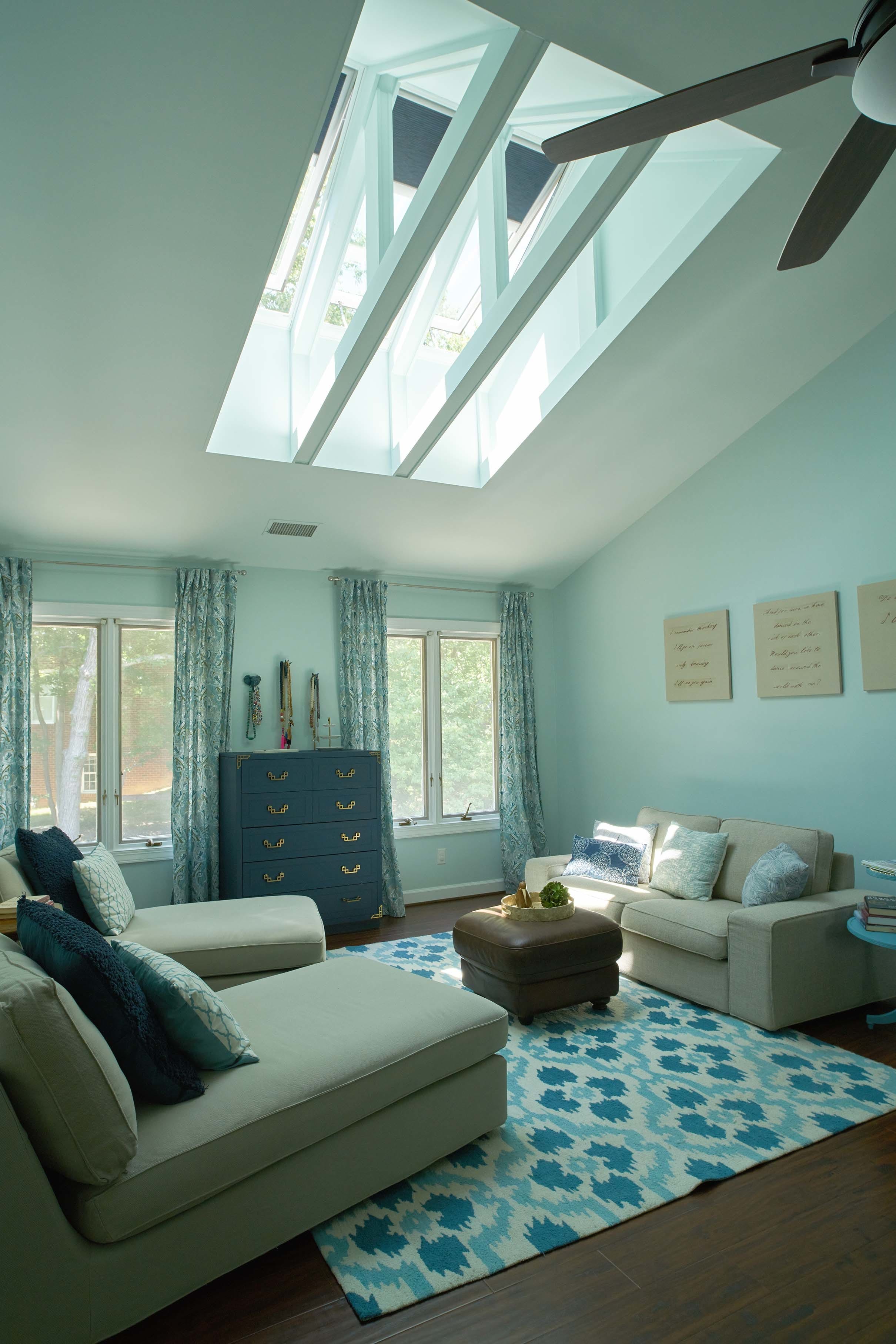 three skylights installed in between exposed roof trusses over a blue and green living room