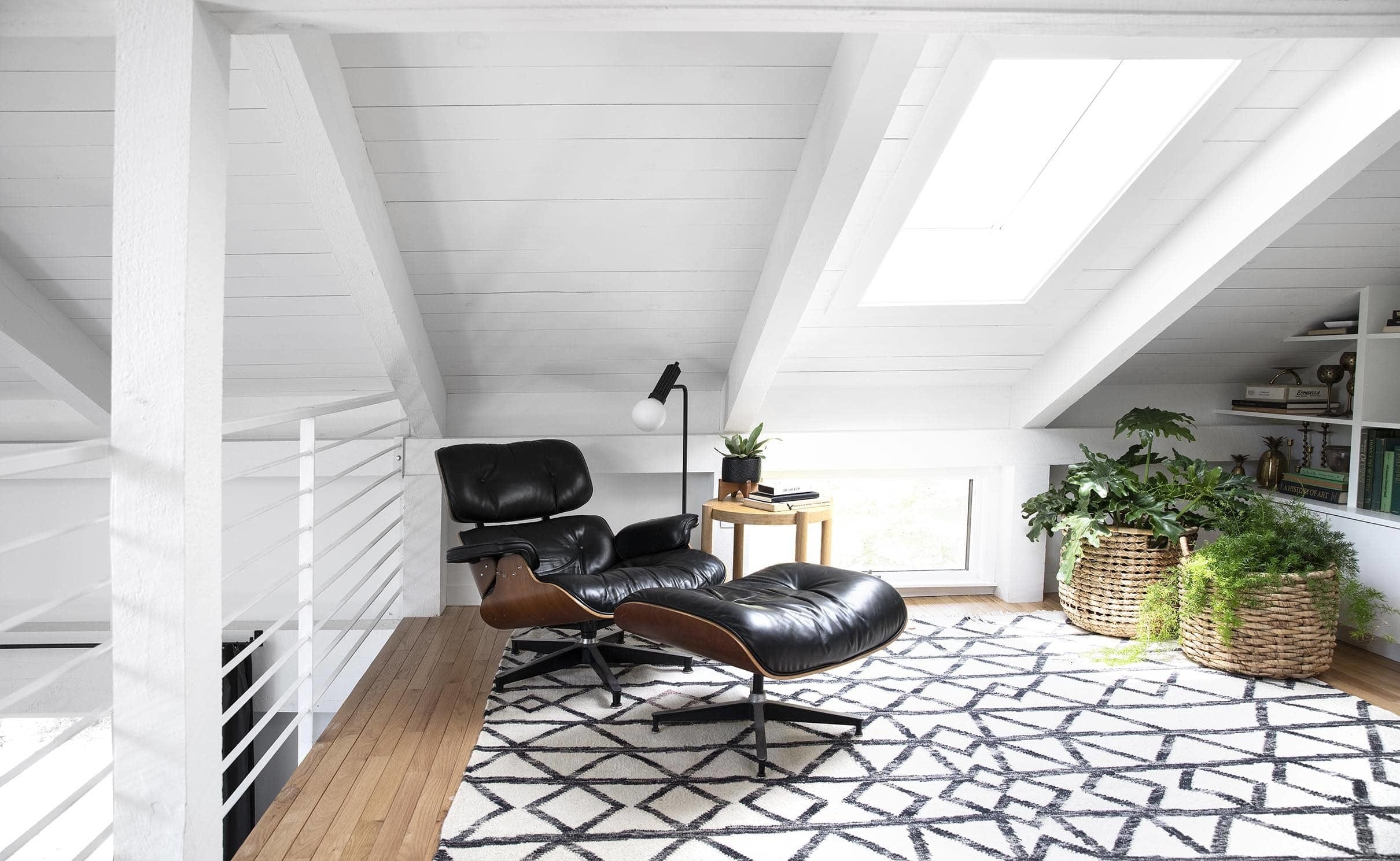 loft with skylight and black lounge chair white painted wood ceiling
