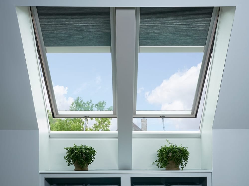 Two skylights with gray blinds over a built-in shelf