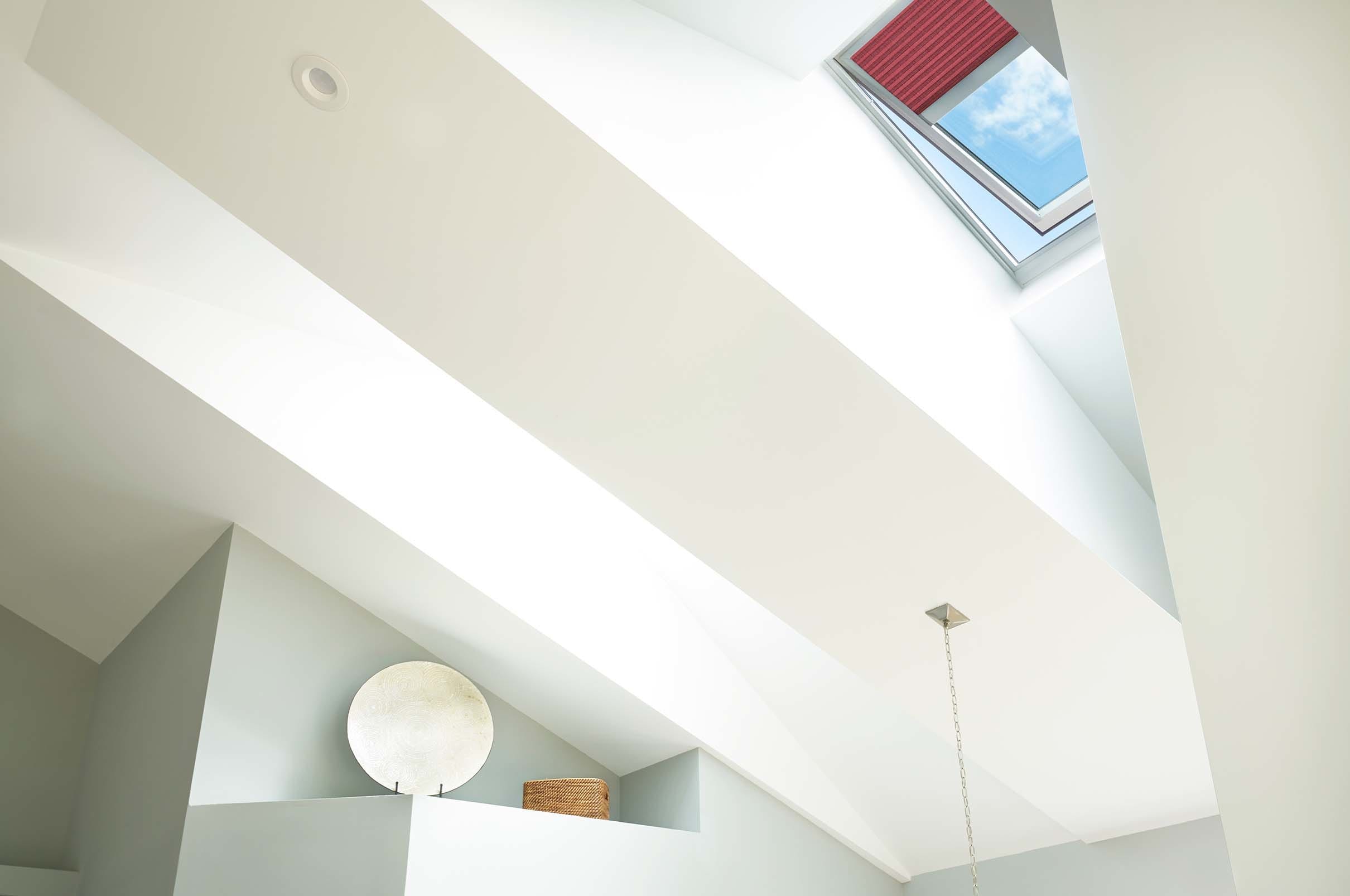 Skylight in a vaulted ceiling with a red shade partially extended