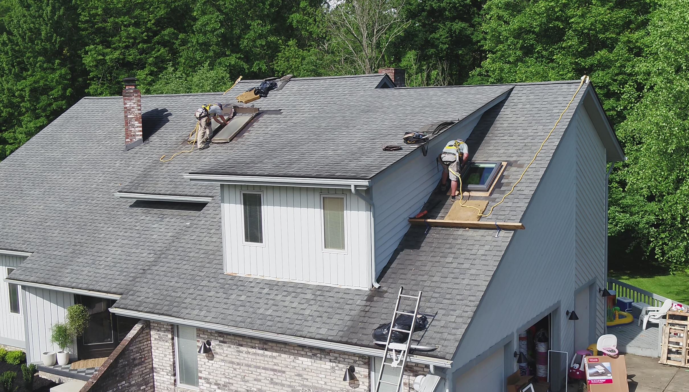 Two workers install skylights on a roof