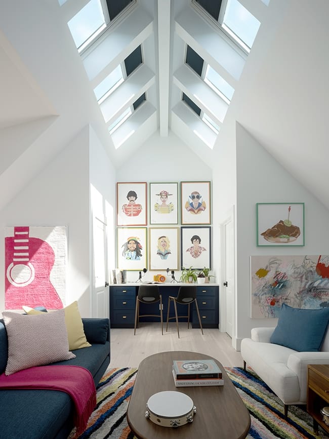 Skylights with shades line the roof ridge in a living room with blue and pink decor