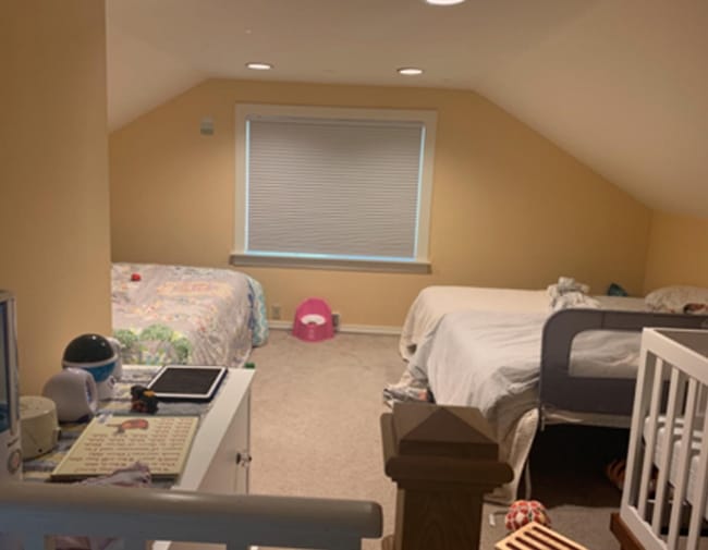 A dark bedroom with yellow walls beds and a crib