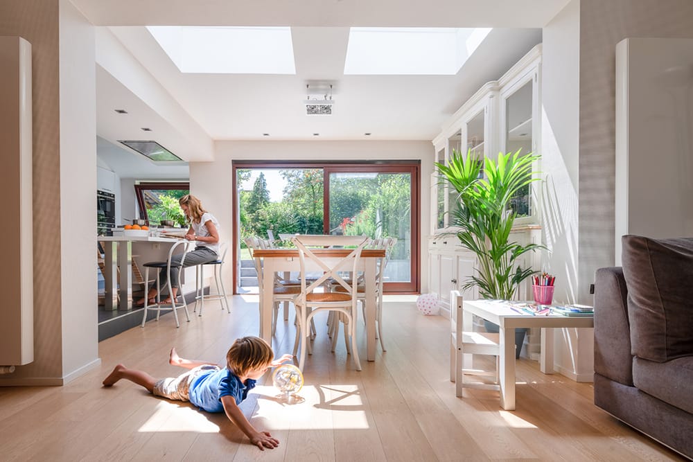 Child playing on the floor in an open-plan kitchen/dining room with skylights