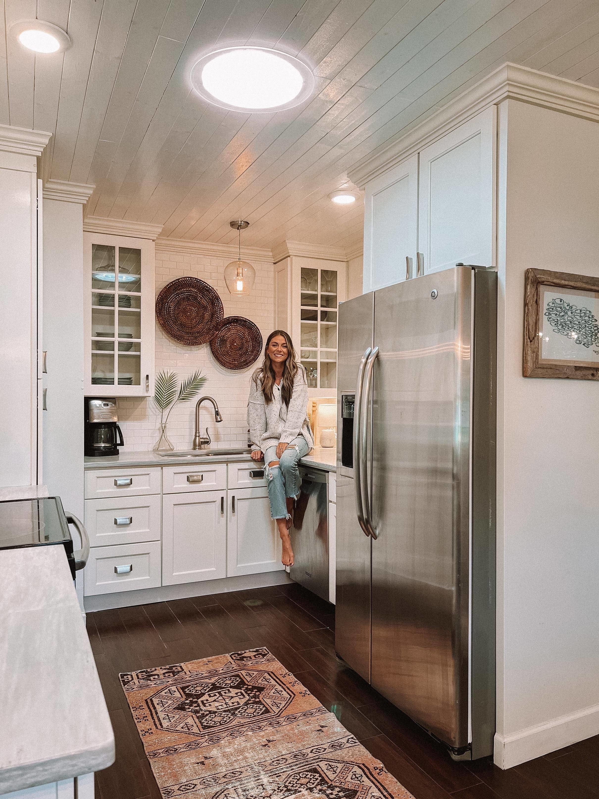 Woman sitting on countertop in white kitchen with Sun Tunnel skylight