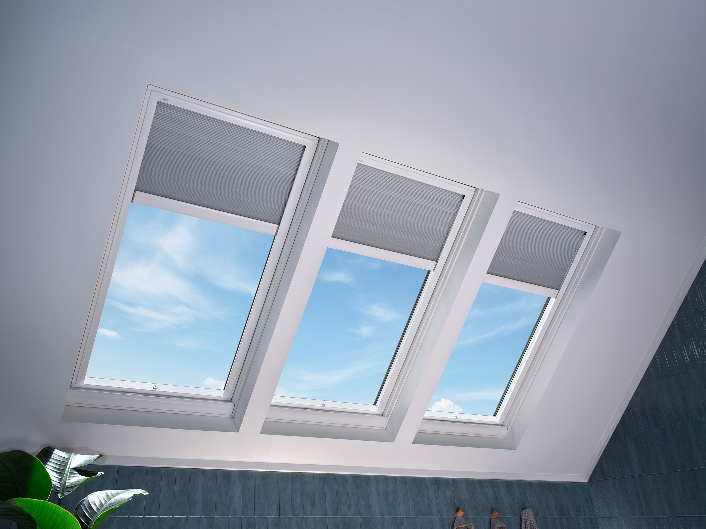 Three closed VELUX venting skylights with white room-darkening shades in a bathroom.