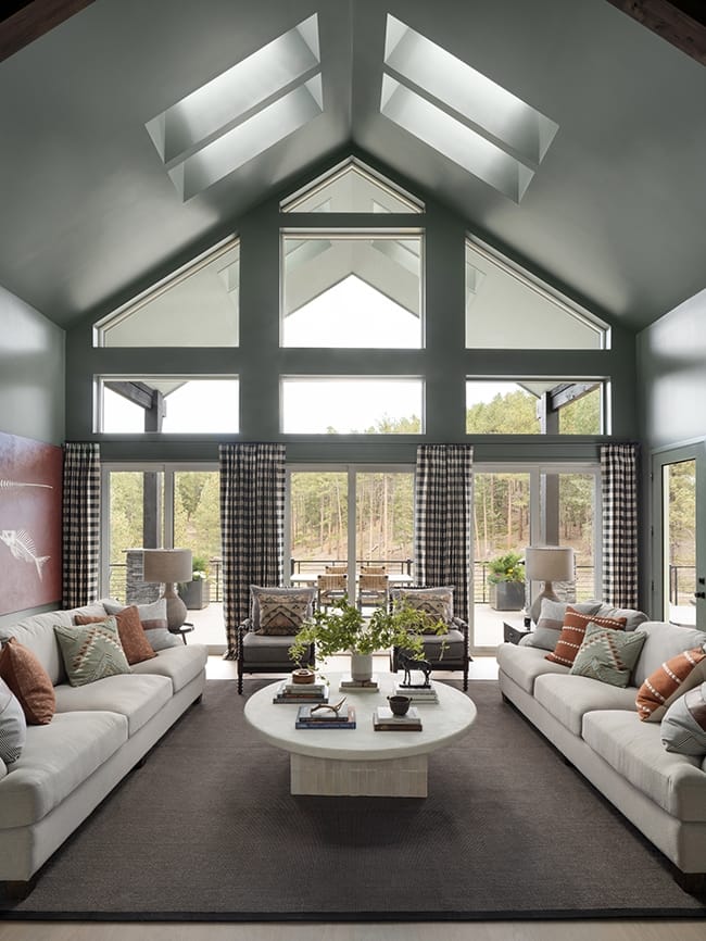 Living room with gray green walls four skylights white couches and a mountain view