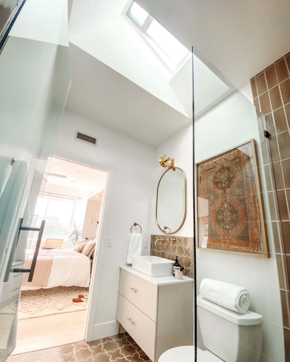 small bathroom with a skylight tan tile and a bras frame mirror