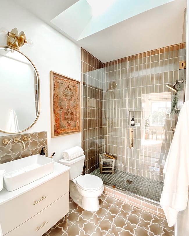 Taupe bathroom with skylight and large cirular mirror over vanity