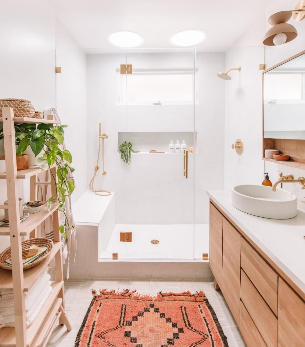 Small bathroom with white and natural wood, rose patterned rug and two Sun Tunnel skylights